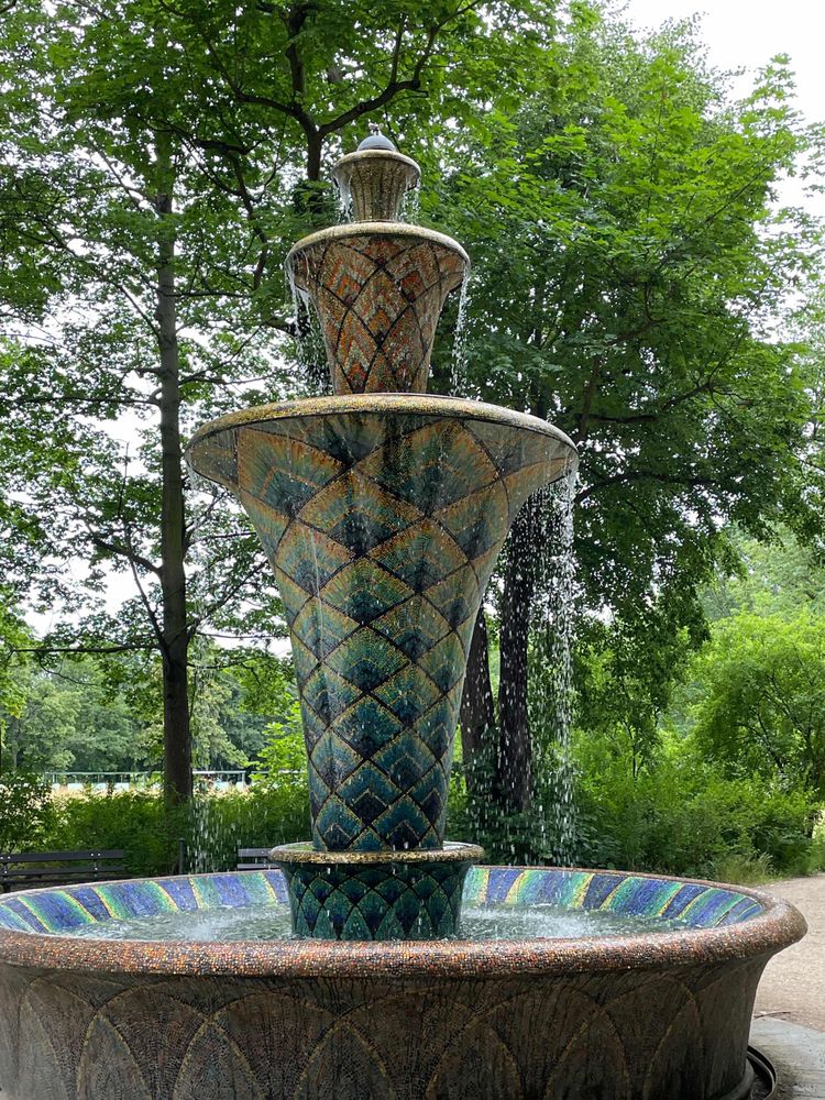 Fountain with colorful mosaic and park train 🚂 in background 