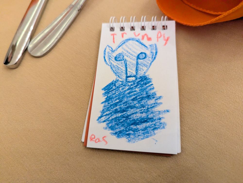 With blue crayon My kid drew Trumpy the alien from Pod People of MST3K fame, in a small notepad 