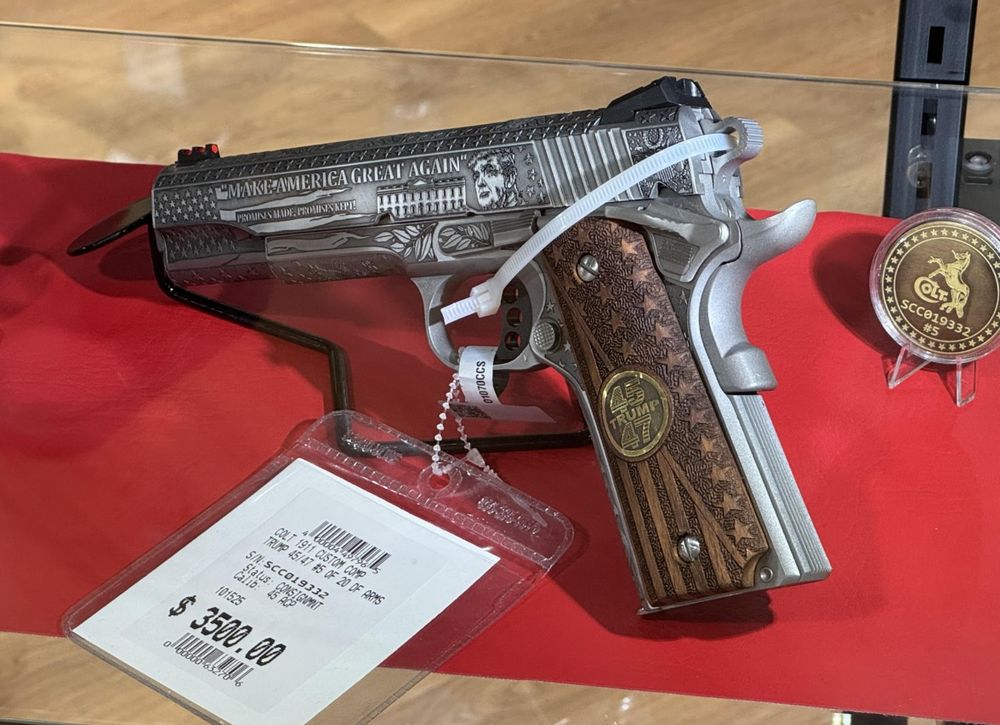A Colt 1911 handgun that has been engraved completely, with Trump crap, a weird Trump face, MAKE AMERICA GREAT AGAIN 45/47 stars, more stars, tag says "CONSINGMENT, $3500.00"