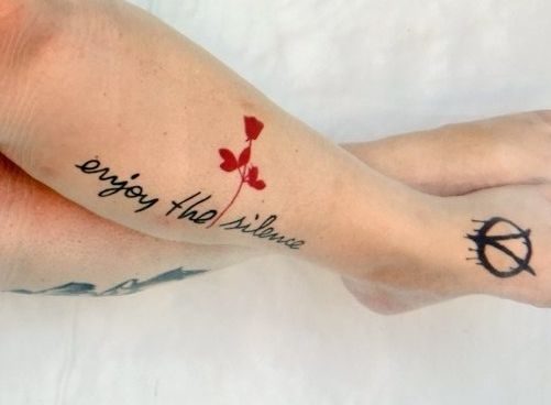 Un tatouage où il est écrit Enjoy the silence avec une rose rouge.