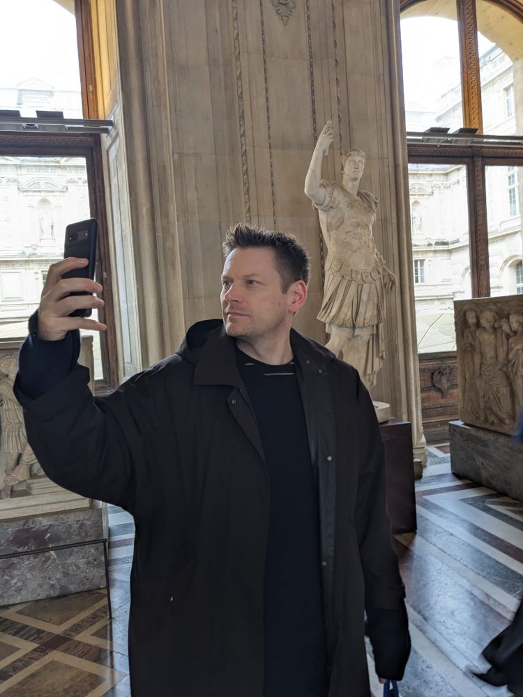 Man takes selfies in front of a Roman statue taking a selfie