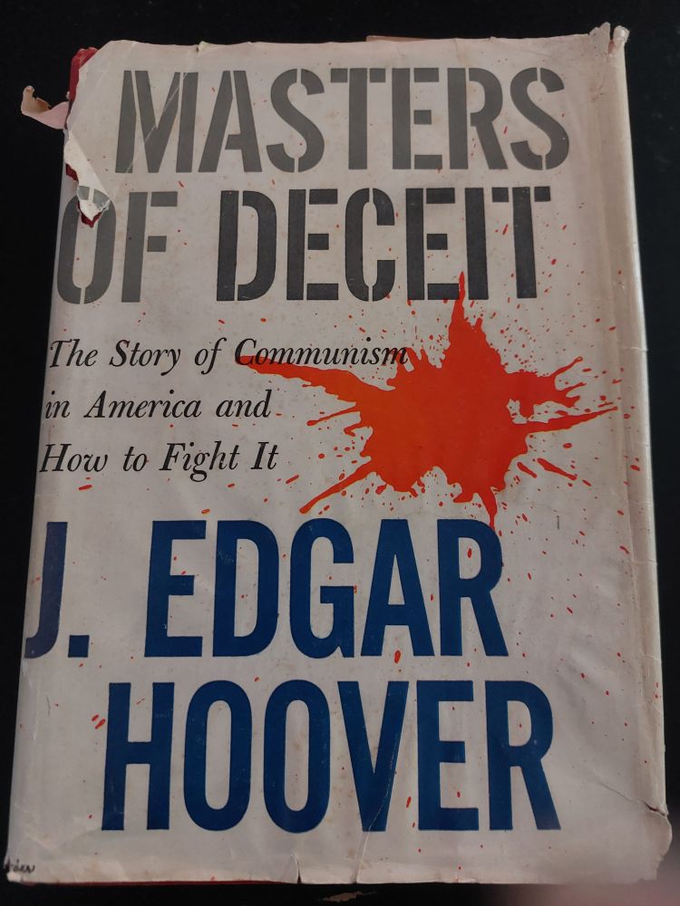 A decrepit hardcover book with dust jacket, "Masters of Deceit: The Story of Communism in America and How to Fight It" by J. Edgar Hoover