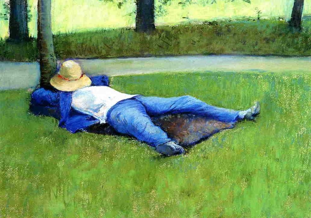 A boy wearing blue pants and jacket with white shirt naps on the grass with a straw hat covering his face
