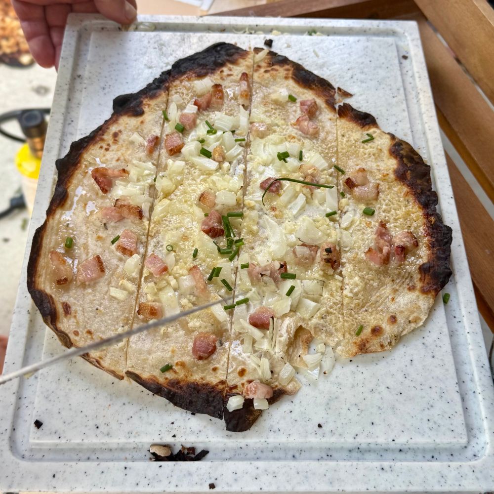 Picture of a palatinate flammkuchen, kind of a pizza with sour cream, onions and bacon.