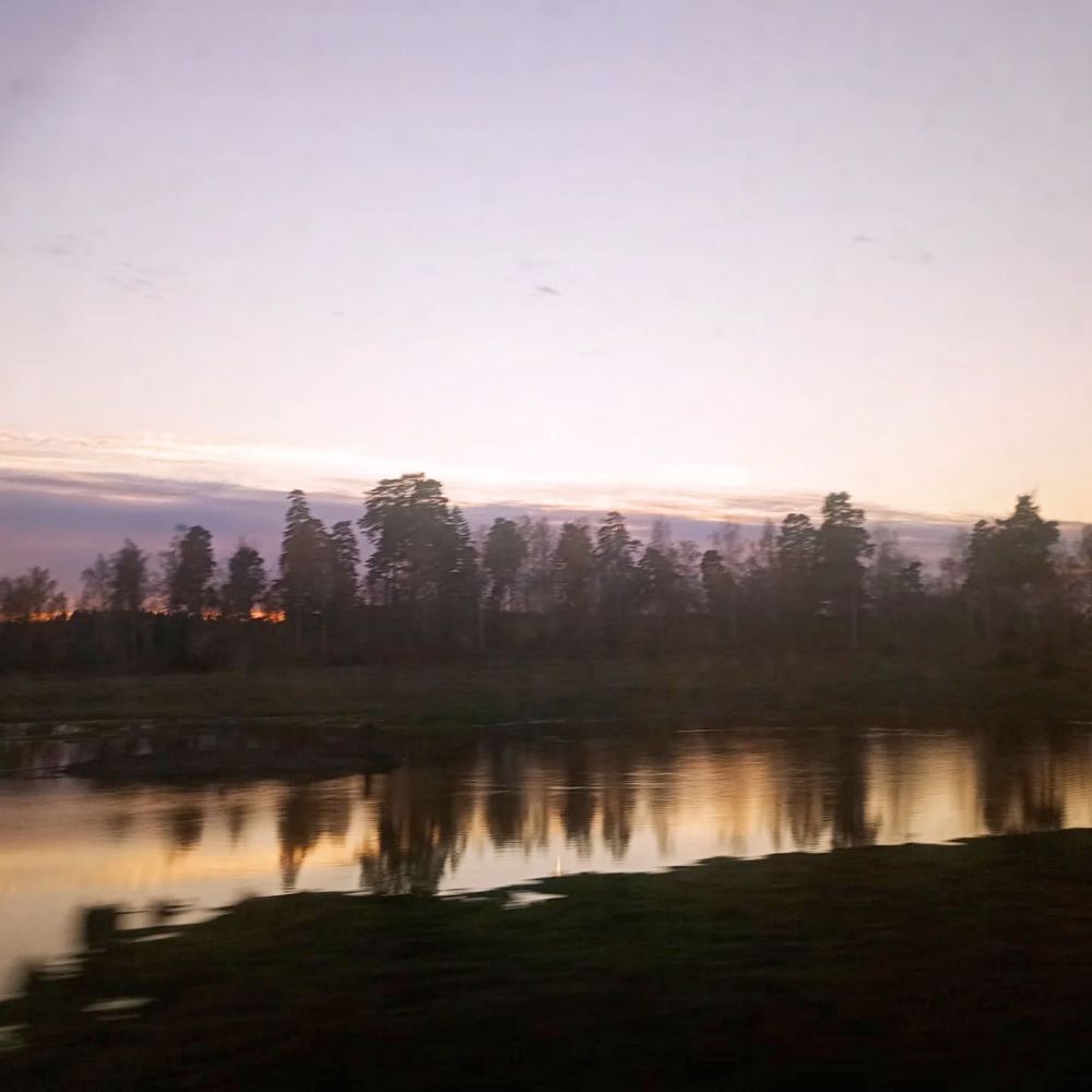 Lake with shining reflection, with trees and evening sky.