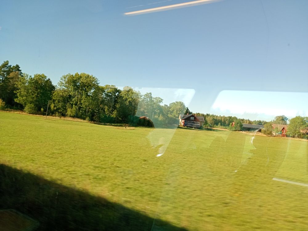 Green fields and groves, blue skies, travelling through Västergötland.