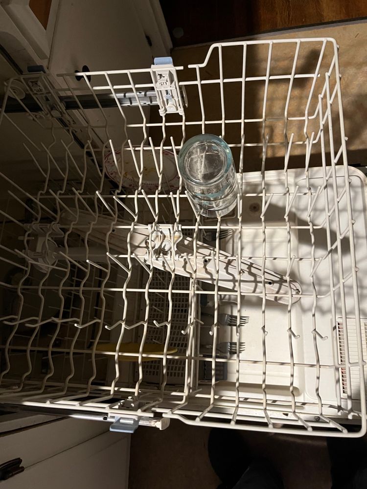 Empty top rack of a dishwasher and a gifted boyfriend has chosen to load a single glass smack in the middle thereby deciding the rest of the rack should be loaded around this monument.