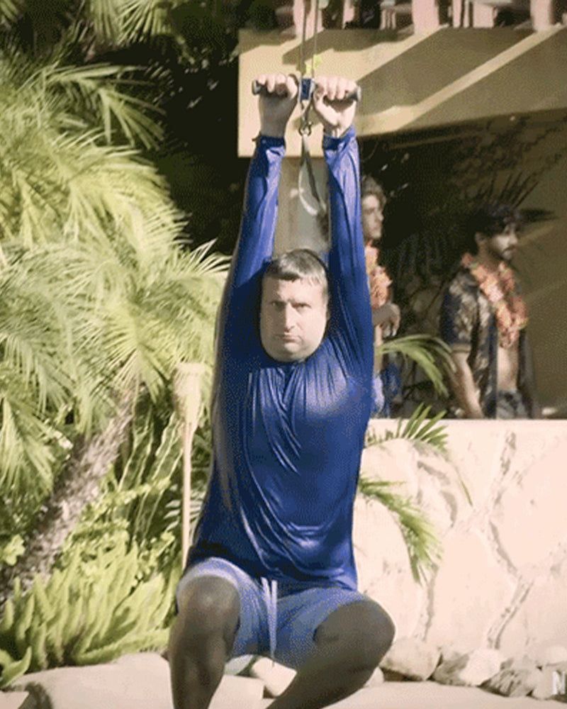 Actor Tim Robinson in wet clothes riding a zip line.