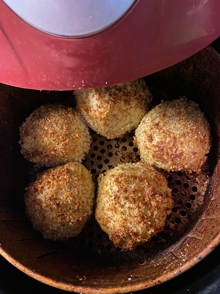 Five homemade arancini’s inside an air fryer basket 