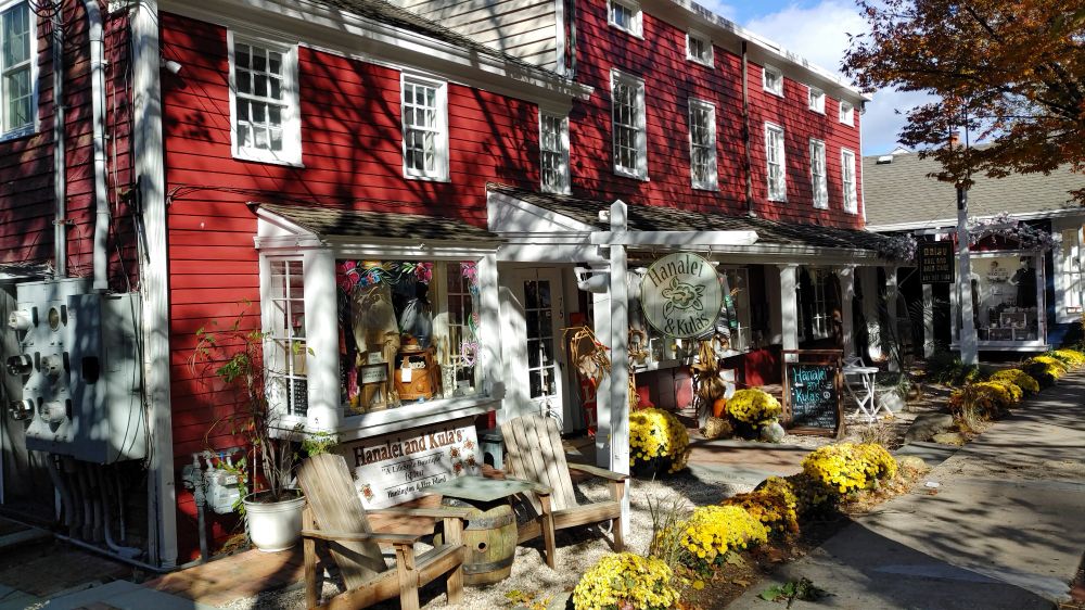 Shops in a series of connected red houses, with the shadows of trees on their façades