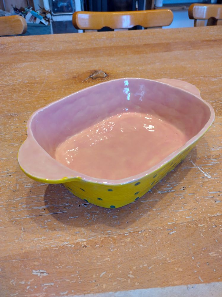 Rosa Schüssel für Lasagne auf Tisch, mit Holzwurm löcher.