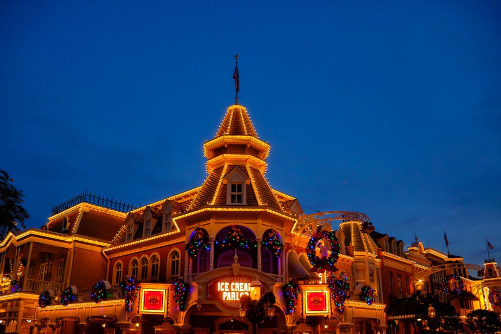 Ice cream parlor at Walt Disney World Magic Kingdom Main Street at dusk with Christmas lights and garlands.