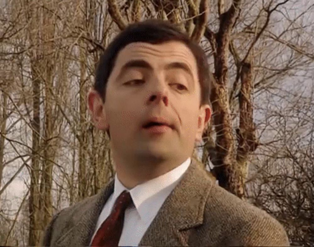 mr bean is wearing a suit and tie and making a funny face .