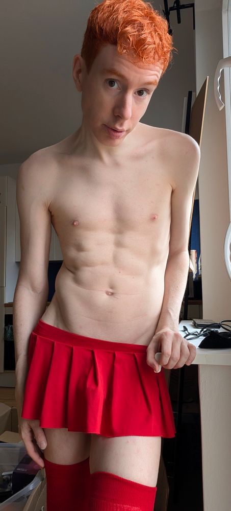 Toned redhead femboy in bright red skirt and red thigh highs