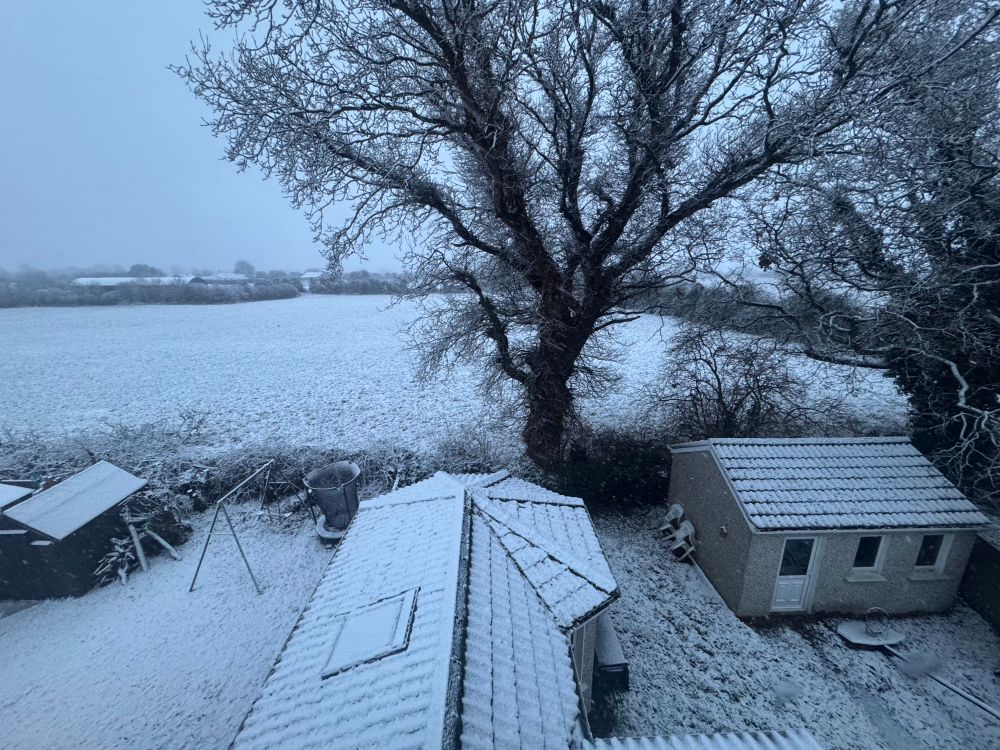 A house roof and field with a dusting of snow. 