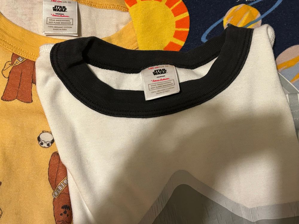 3 pairs of PJs laying flat. Left to right they have a wookie and a little white ball shaped animal, a white armour costume, and the planets of our solar system 