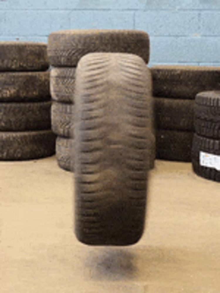 a tire is floating in the air near a pile of tires