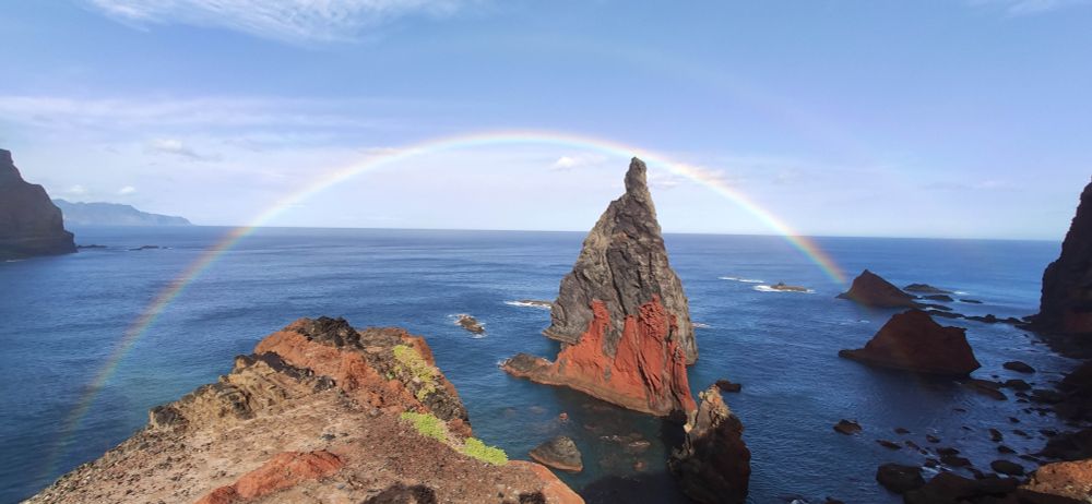Rainbow over rocky outcrops on the coast with the sea below