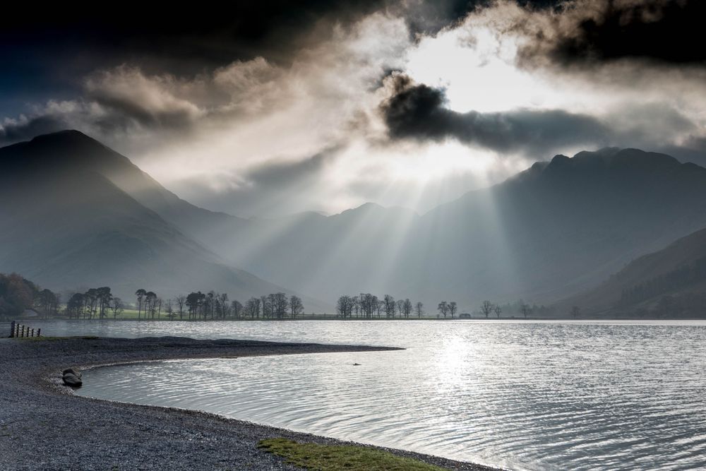 Sun beams shining through winder cloud onto lake.