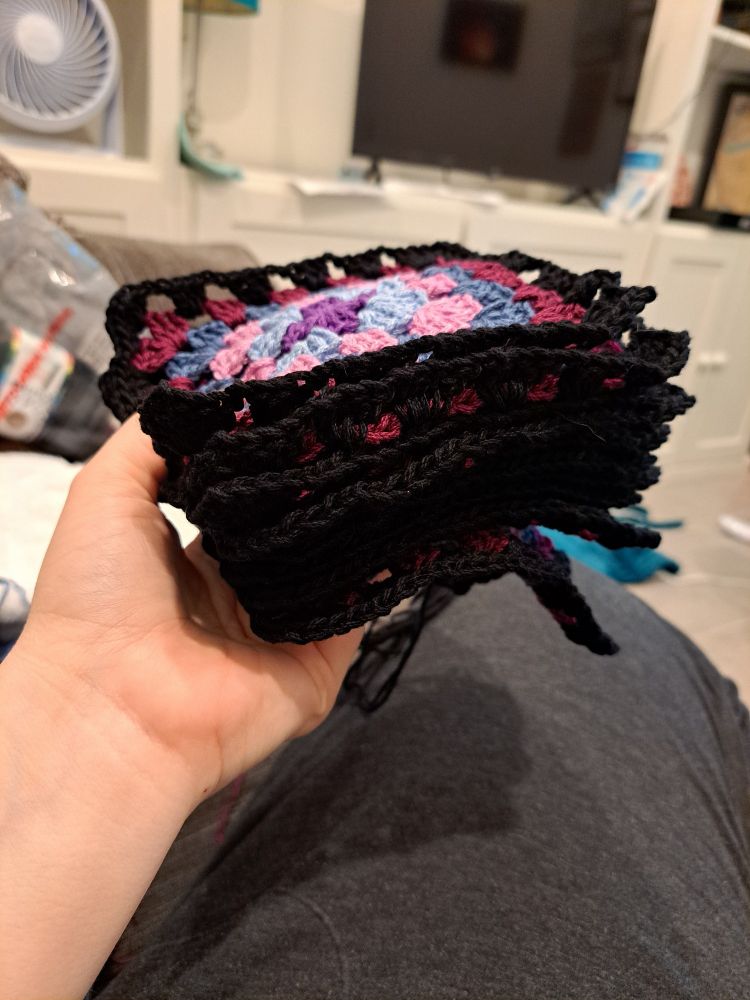 I am holding a stack of granny squares that I've been working on since yesterday. 
