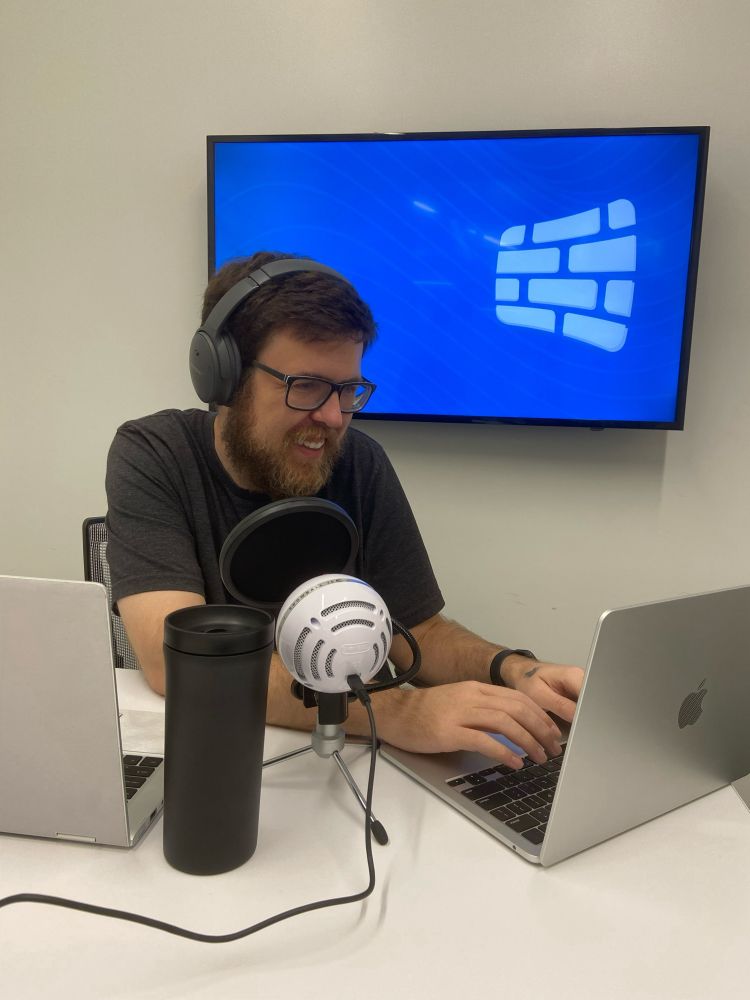 iotamega working on a laptop with microphone and the Founders logo on the screen behind him.