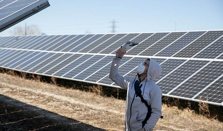A student uses a tool to measure photovoltaic power potential at newly installed solar panels.