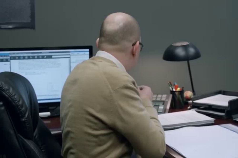 a man sits at a desk in front of a computer screen