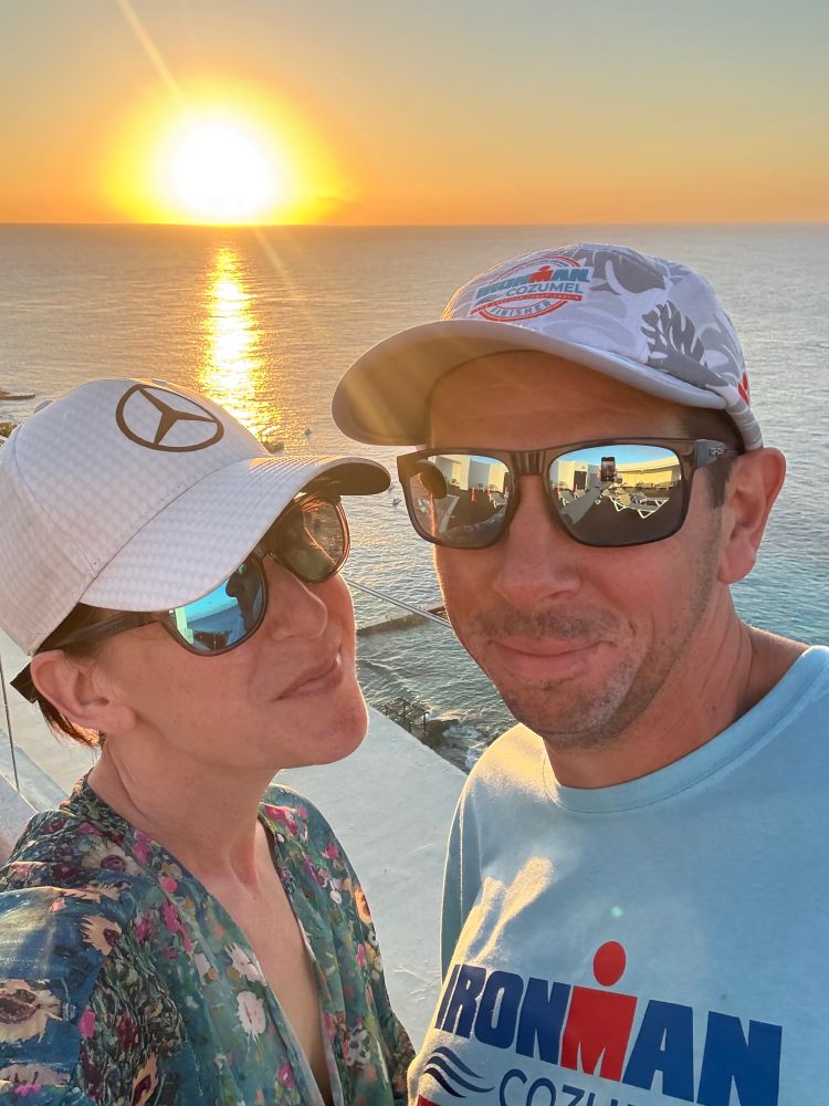 A couple posing for a selfie at sunset with the ocean in the background.