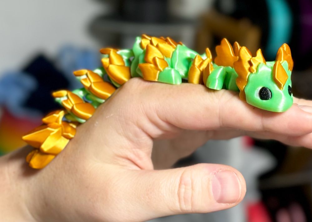 A mint green dragon with gold scale accents and a gold gem shape on it’s forehead 