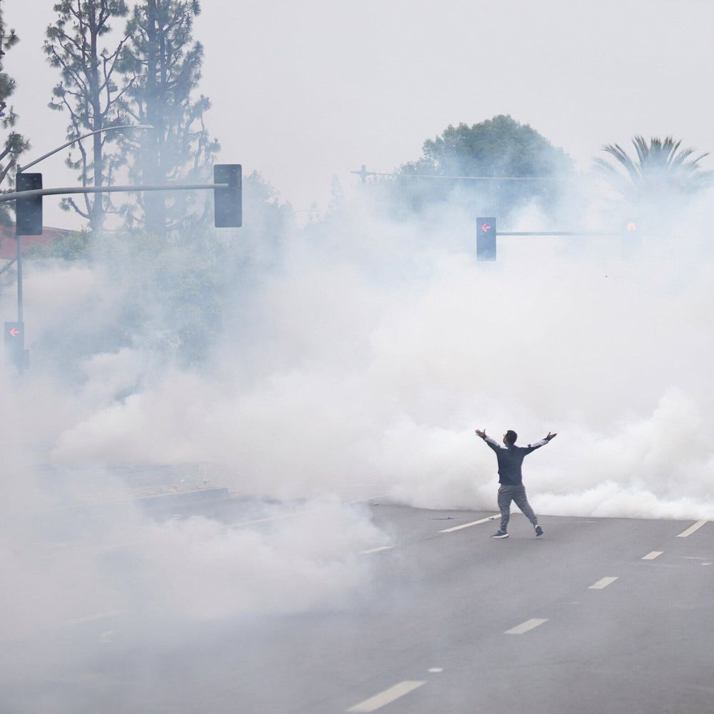 Protester faces a giant cloud of tear gas with arms outstretched
