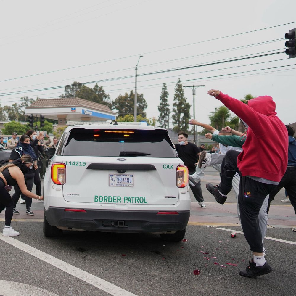 White vehicle with Border Patrol written in green on the back is attacked by protesters 