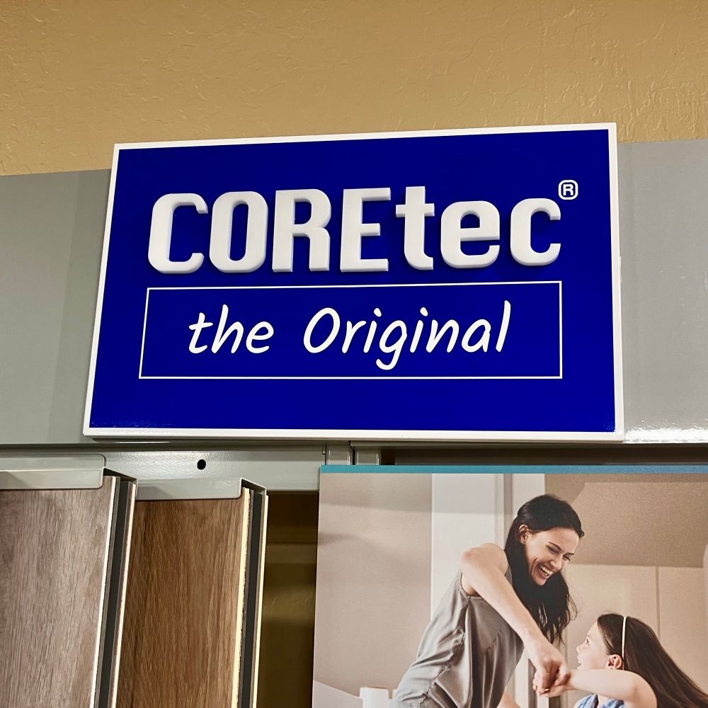 A sign above a flooring display that reads "COREtec / the Original". The first line is set large in Apple’s Macintosh Chicago font. The second line is set smaller in something that resembles Comic Sans.