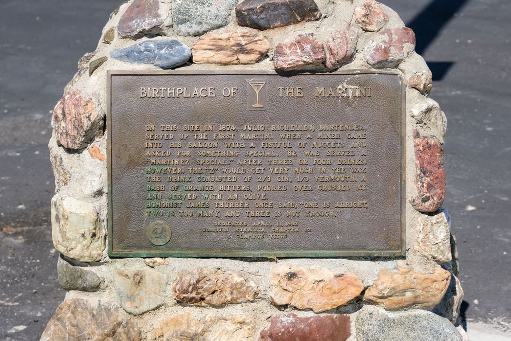A metal plaque set in rock and concrete which reads:

BIRTHPLACE OF 🍸 THE MARTINI

ON THIS SITE IN 1874, JULIO RICHELIEU, BARTENDER, SERVED UP THE FIRST MARTINI WHEN A WINER CAME INTO HIS SALOON WITH A FISTFUL OF NUGGETS AND ASKED FOR SOMETHING SPECIAL. HE WAS SERVED “MARTINEZ SPECIAL.” AFTER THREE OR FOUR DRINKS, HOWEVER, THE “Z” WOULD GET VERY MUCH IN THE WAY. THE DRINK CONSISTED OF 2/3 GIN, 1/3 VERMOUTH, A DASH OF ORANGE BITTERS, POURED OVEN CRUSHED ICE AND SERVED WITH AN OLIVE. HUMORIST JAMES THURBER ONCE SAID, “ONE IS ALRIGHT, TWO IS TOO MANY, AND THREE IS NOT ENOUGH.”

DEDICATED APRIL 11, 1992
JOAQUIN MURRIETA CHAPTER 13
E CLAUMPUS VITUS