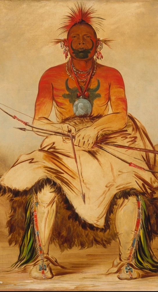 A painting of a Native American sitting in a chair with red paint and buffalo designs in black paint on his face and chest. He is holding a bow and arrow in his lap as though ready to draw the arrow and is wearing leather pants and moccasins embellished with colored decorative patterns. The painting is by George Catlin. Image in the public domain via Smithsonian American Art Museum.
Description from the museum:
Buffalo Bull appears "with his medicine or totem (the head of a buffalo) painted on his breast and his face, with bow and arrow in his hands." This unfinished portrait provides a key to Catlin's working methods in the West, where he had to work quickly. During Buffalo Bull's sitting, Catlin focused on his face and his totem (the buffalo head painted on his chest, partially hidden behind a large peace medal). The artist usually finished bodies and costume details in an urban studio. 