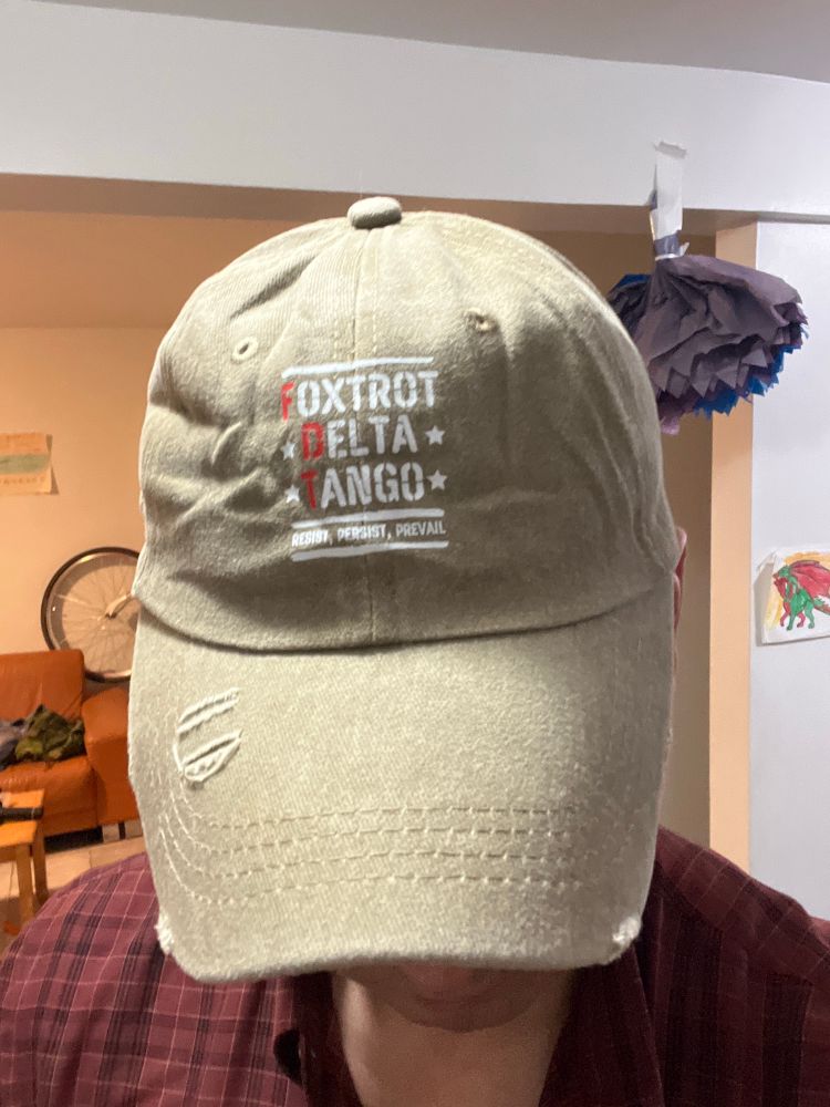 The hat reads:
Foxtrot (fuck))
Delta (Donald)
Tango (Trump)
Underneath: Resist • Persist • Prevail