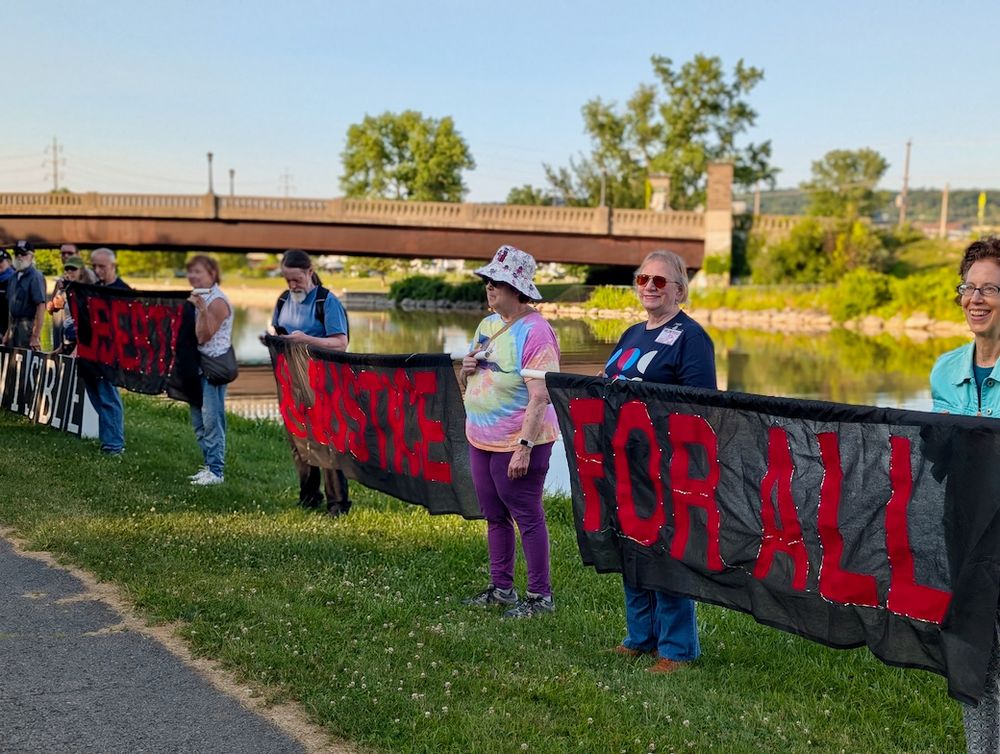 Several people lined up, holding lighted banners that read "LIBERTY & JUSTICE FOR ALL"