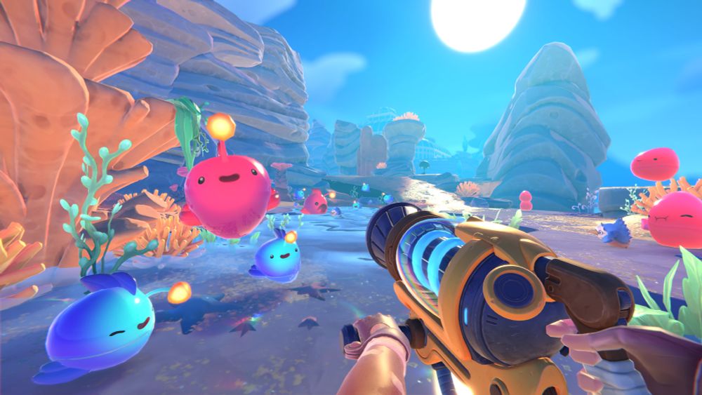 Capture d'écran d'un jeu en 3D cartoon, très lumineux et coloré. On tient une arme futuriste (en réalité un aspirateur) braqué sur de gros blobs bleus et rouges qui sautillent joyeusement.