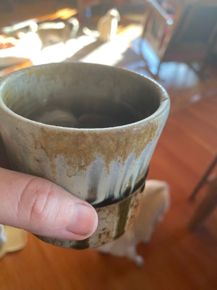 A pottery cup with some iced tea made with herbal tea blend