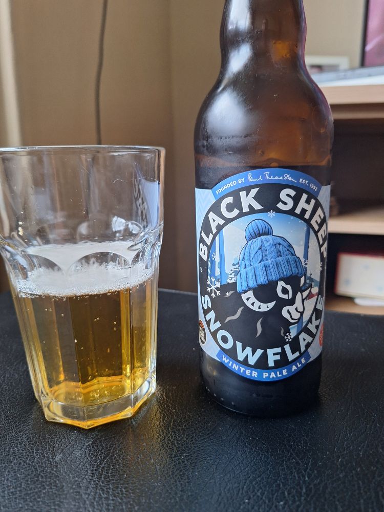A bottle of Black Sheep Snowflake pale ale with a glass half full of beer.