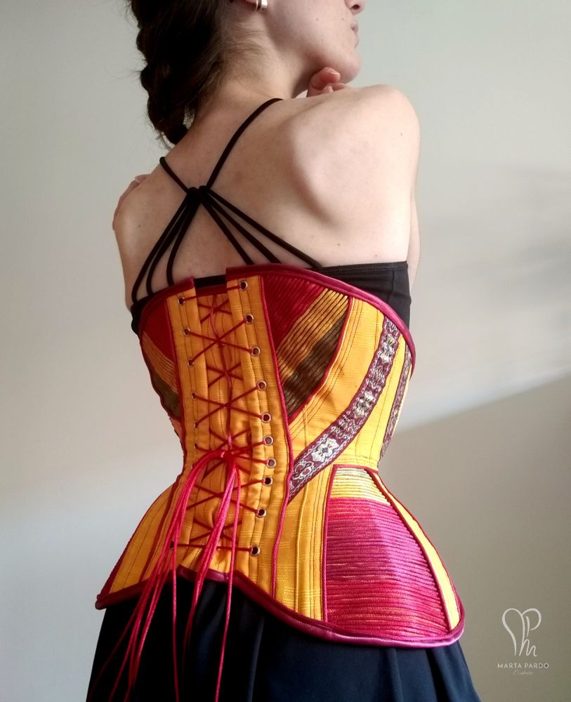 Back view of sample corset I made back in 2020. I drafted the pattern taking inspiration from Edwardian styles, and modernized the finishings. Front zip closure, floating fashion layer with visible colourful cording. Structural layer of coutil and steel boning is invisible from the outside.