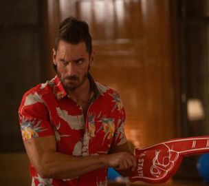 Derek Wilson as Wolf, wearing a red Hawaiian shirt and a red foam 👆hand 