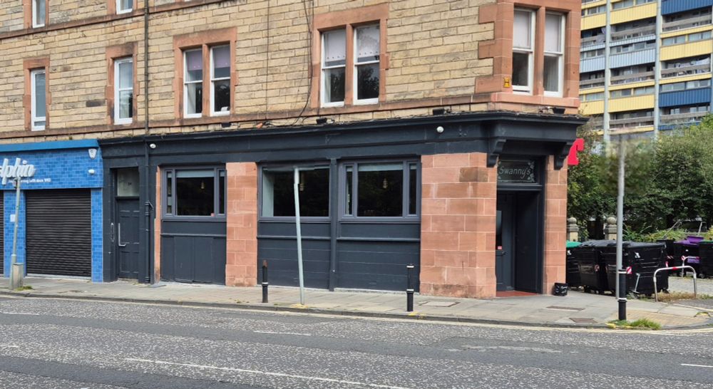 Exterior view of a pub called Swannys , painted grey.