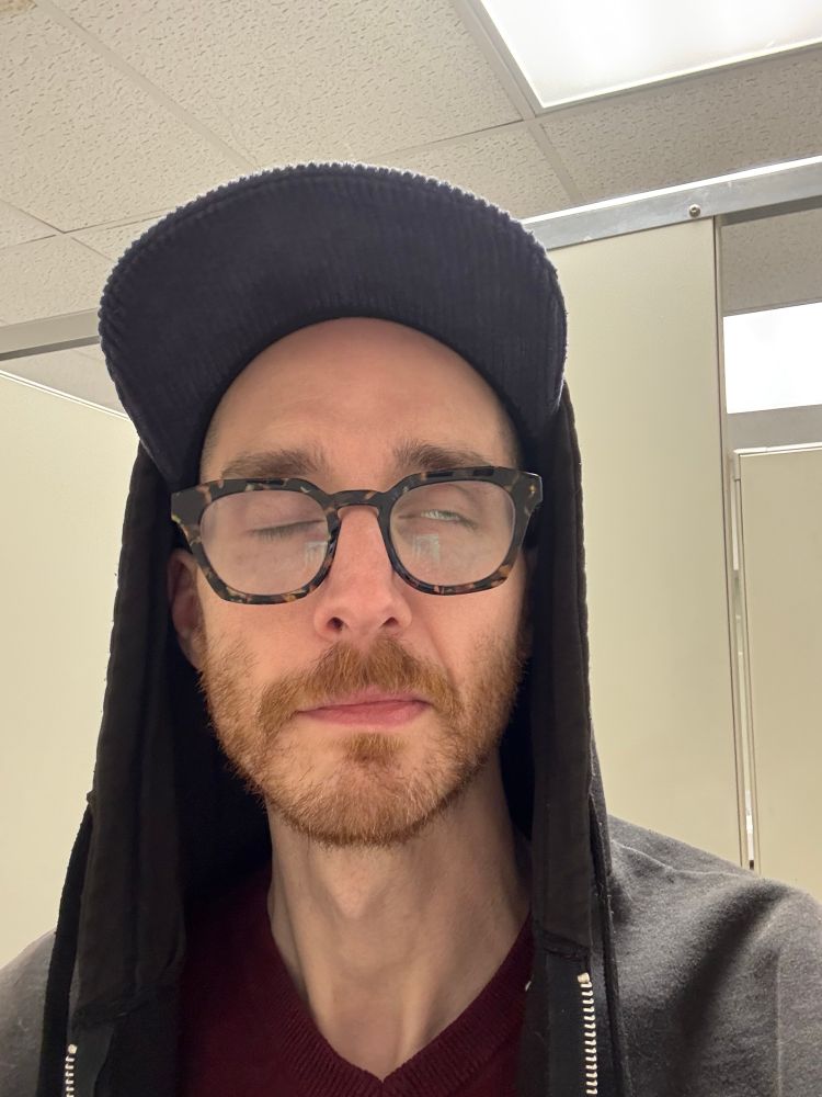 selfie of me in work bathroom stall, one of my eyes is shut (right) while the other (left) is a bit open, showing mostly the white and a tiny bit of the iris