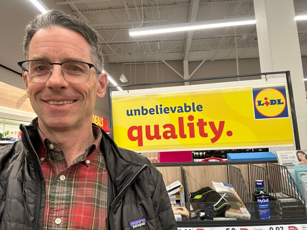 Self in front of a sign that reads “unbelievable quality” with the Lidl logo