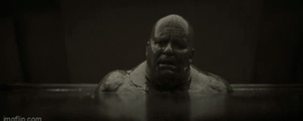 a black and white photo of a man in a bathtub with his mouth open .