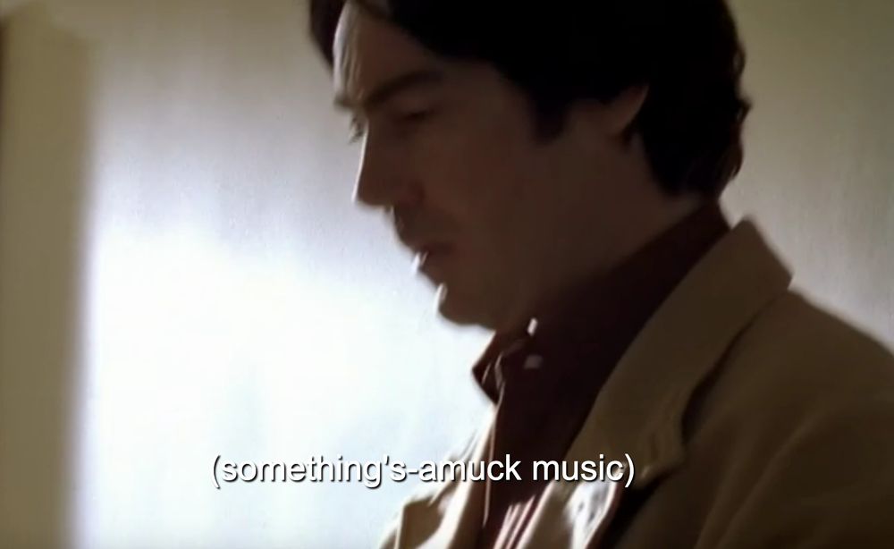 movie screenshot with  "(something's amuck [sic] music)" appearing in subtitles, in brackets
