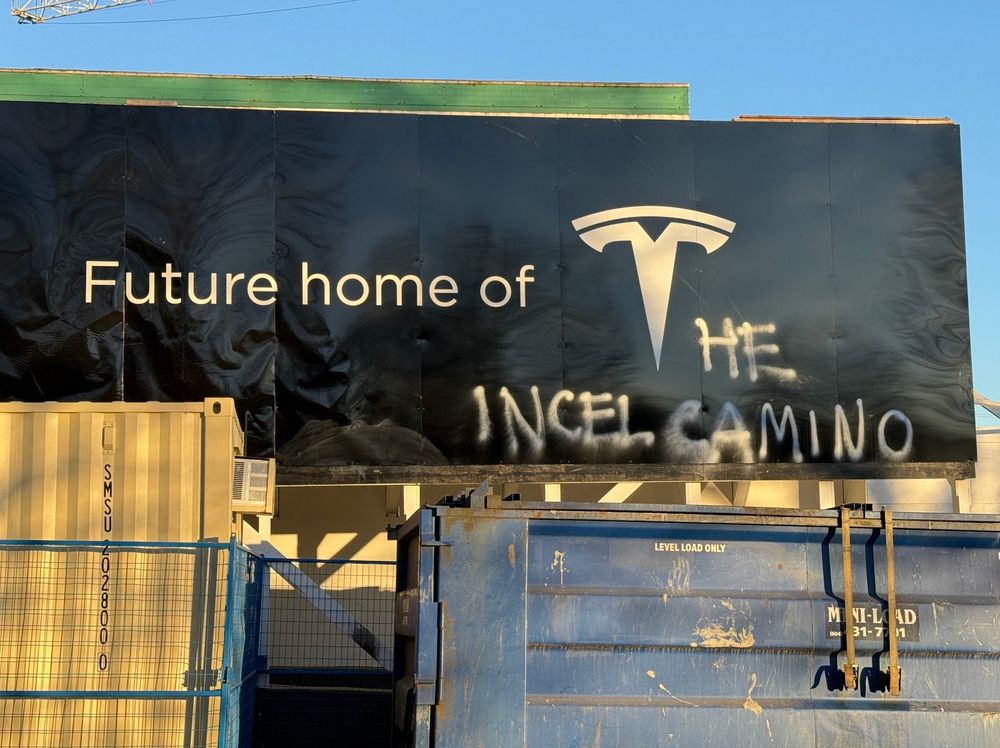Construction hoarding at Prior and Raymur in Vancouver that says "Future home of T" (Tesla logo) but someone has changed it to read "The Future home of T( Incel Camino)"