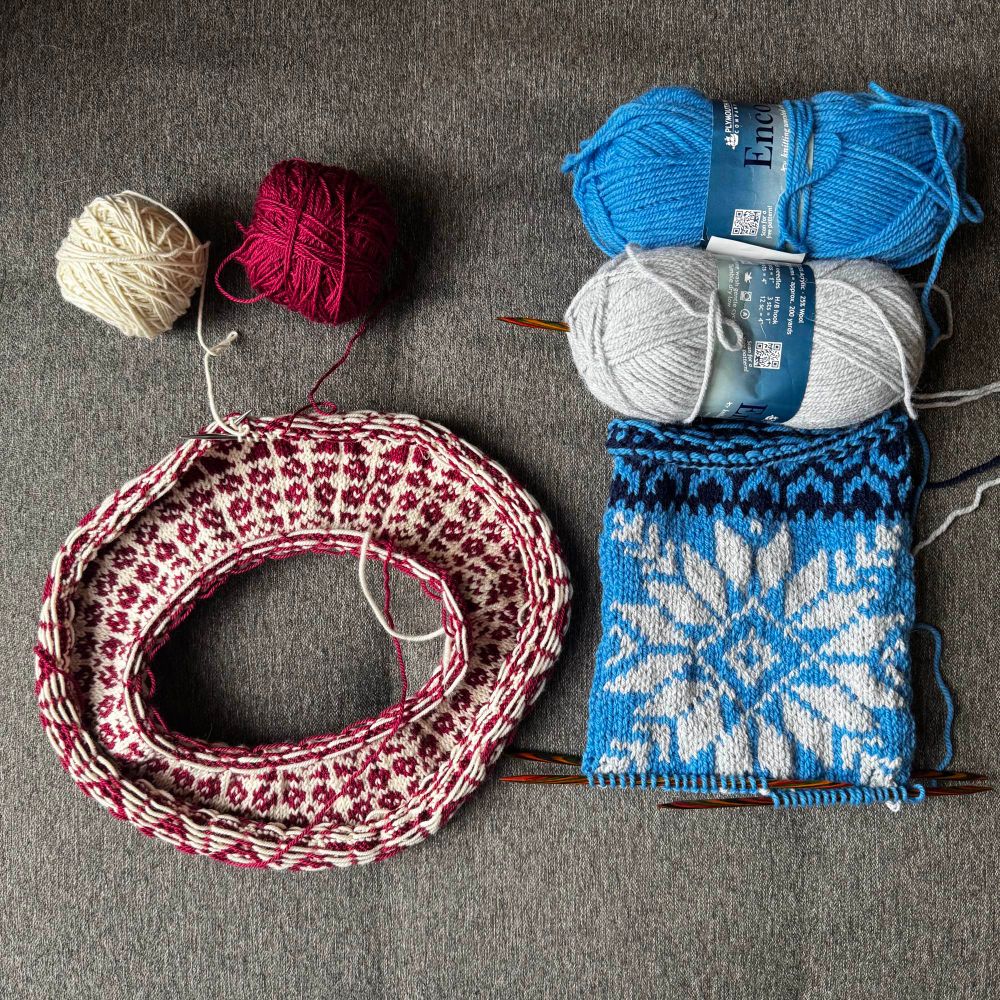 Two knitting projects in progress.

On the left is child sweater (Compass by Tin Can Knits) with a colorwork yoke being knit with a dark red (super old Louet Gems Sportweight) and white (undyed KnitPicks High Desert Sport).

To the right is the start of a Christmas stocking knit in two shade of blue and light grey. I’m winging the pattern as I go, using colorwork patterns from other patterns and stitch dictionaries. Yarn is Plymouth Yarns Encore.