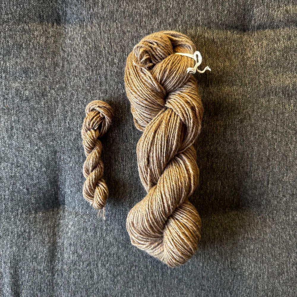 2 skeins of golden brown handspun yarn. The larger one is a true 3-ply and was skeined on a 2-yard niddy-noddy.

The smaller skein was chain-plied with leftovers and was sound onto a 1-yard niddy noddy.

The fiber was a Mellyknits blend of 75% Bond, 20% alpaca, and muga silk.