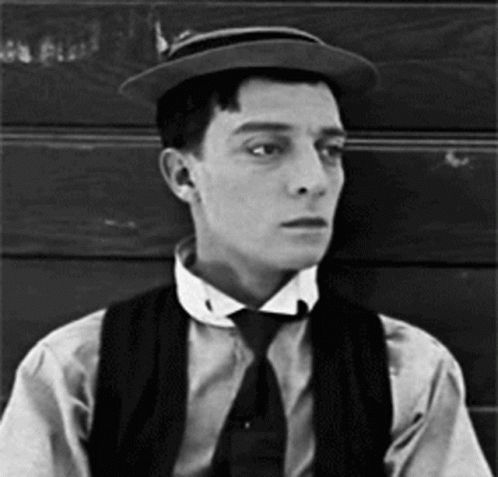 Gif of actor Buster Keaton with a very deadpan expression, tipping his hat to someone off-screen. 